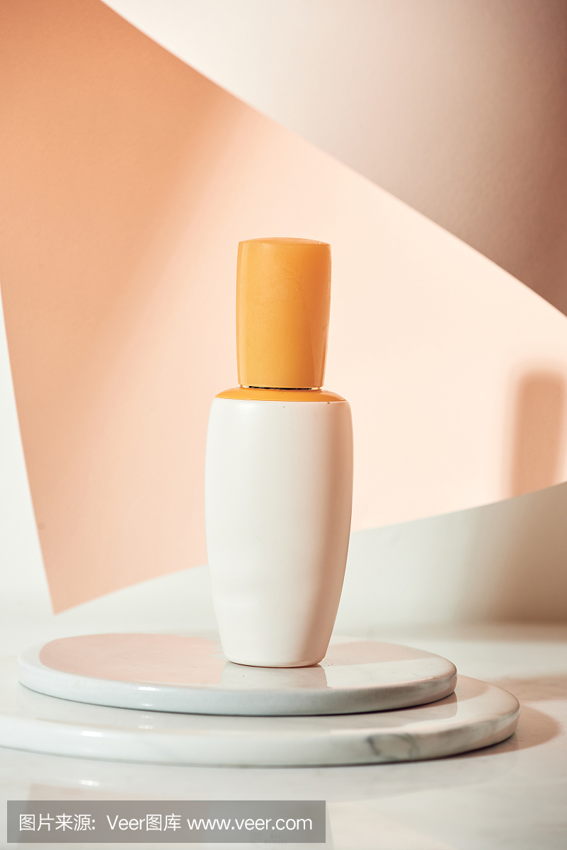 护肤产品血清瓶模型样品造型的米色桌子与粉红色的纸。产品工作室造型拍摄